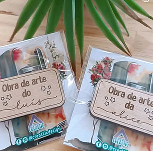 Two engraved wooden plaques reading work of art with a child's name, in Creattic packaging.