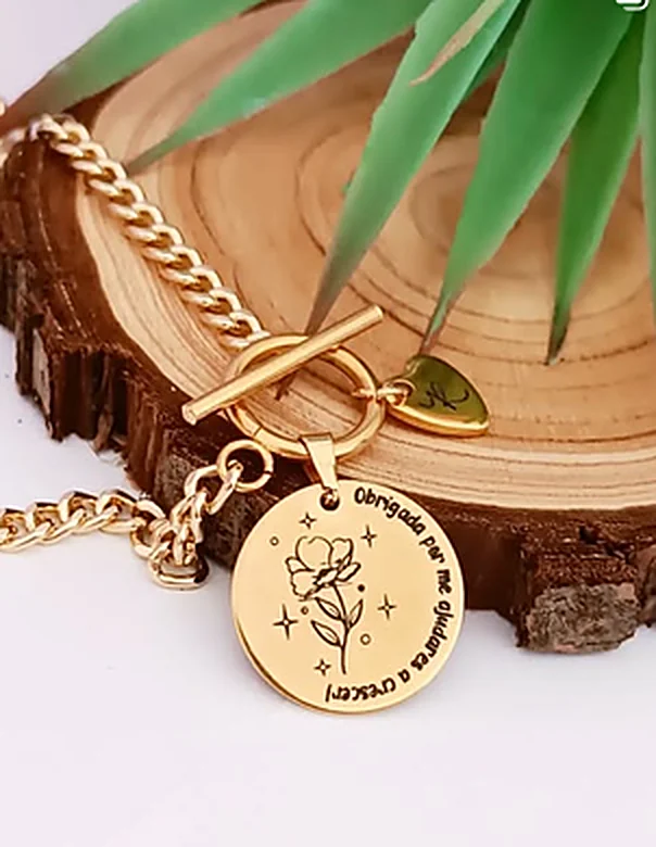 Gold-tone chain bracelet with a toggle clasp and a round medal engraved with a flower and a thank-you line.