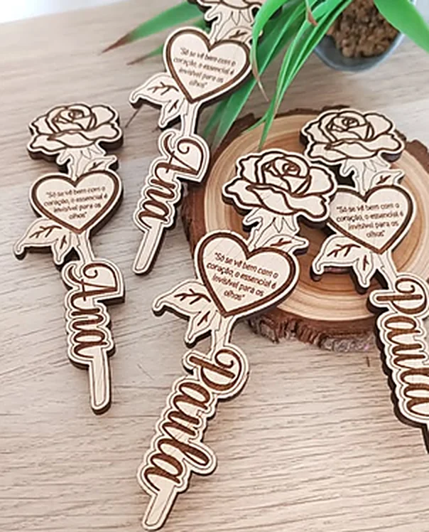 Cut wooden roses, each with a handwritten name along the stem and a line engraved in a heart.